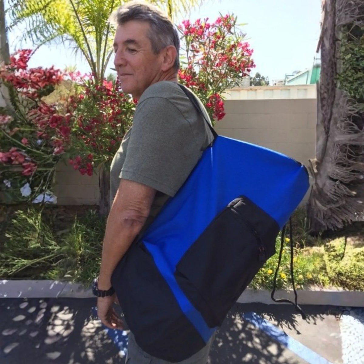 Person carrying EasyDive mini scuba kit in blue and black shoulder carry bag outdoors