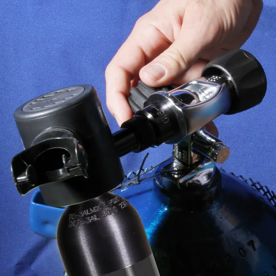 Hand attaching the Spare Air refill adapter to a scuba tank valve during the refill process.
